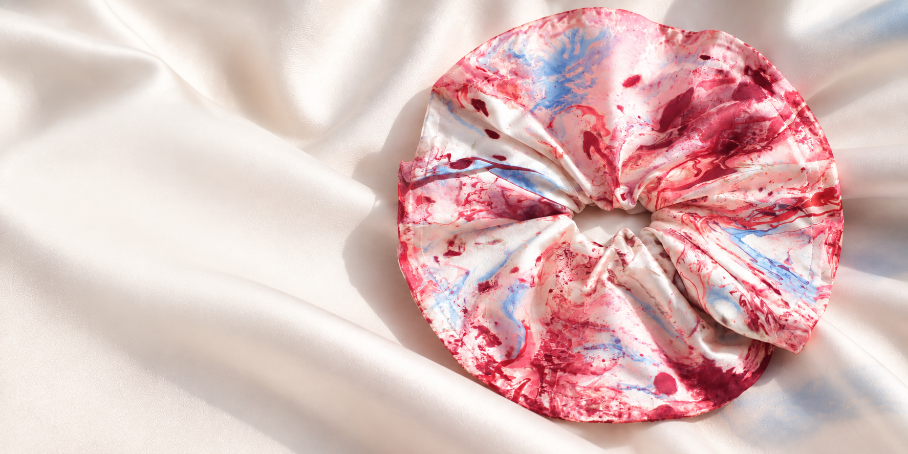 Rose and powder-blue marbled silk scrunchie on flowing white silk